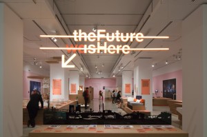Neon welcome sign/exhibition logo hangs over laser-cut graphic of an industrial/technological timeline and points towards the Future Factory